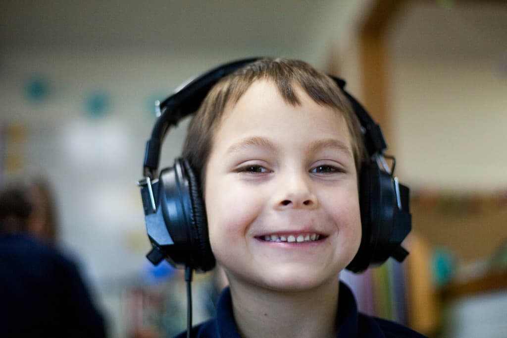 Smiling child wearing audiometric headphones during a hearing screening at school