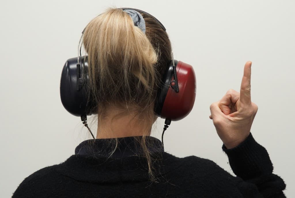Woman wearing audiometric headphones raising a finger during a hearing test