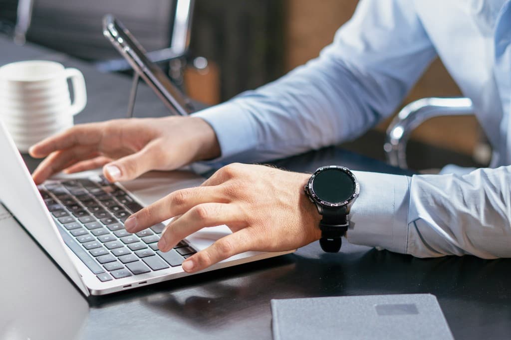 Professional typing on a laptop at a desk, representing digital compliance and reporting