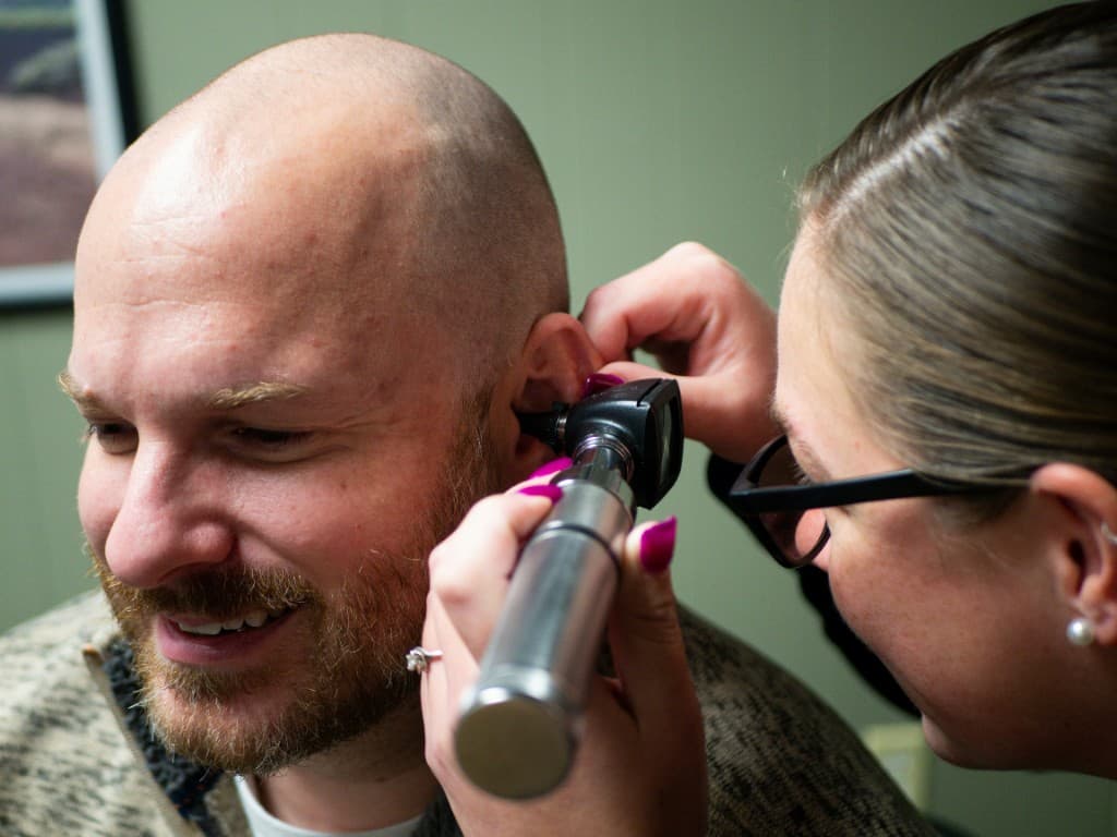 Audiologist examining a patient's ear canal with an otoscope during a professional cerumen check