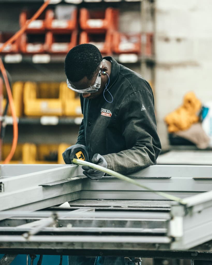Industrial worker in a high-visibility vest and gloves adjusting yellow hearing protection earmuffs on the job